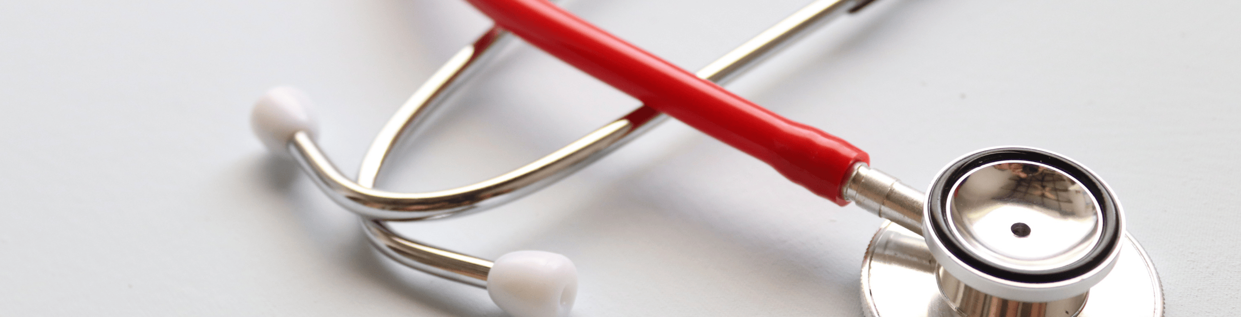 A close-up of a stethoscope with a red tube, resting on a light surface.